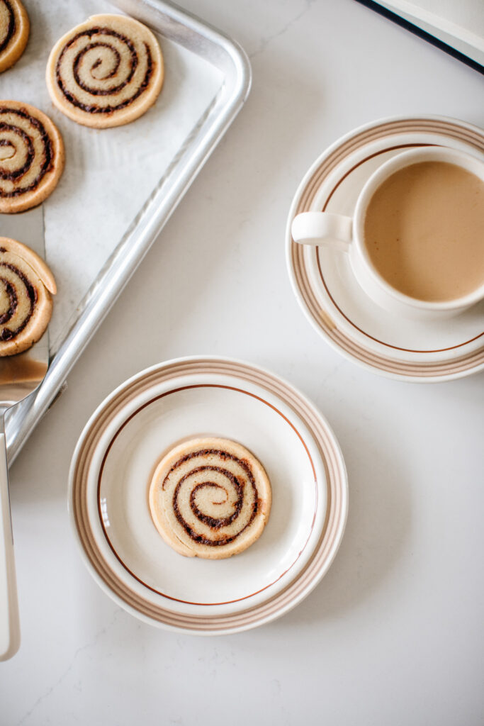 cinnamon roll cookies on a plate beside a cup of coffee